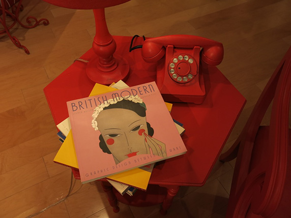 a red phone table with a red phone on it and a few magazines next to the telephone