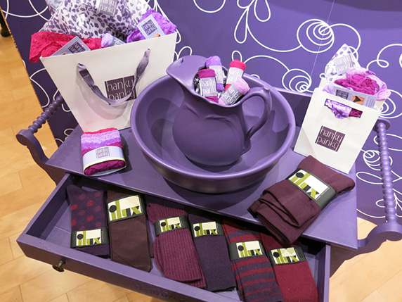 A cabinet with a drawer full of socks. the cabinet is painted in purple like other recipients, and the packages on it