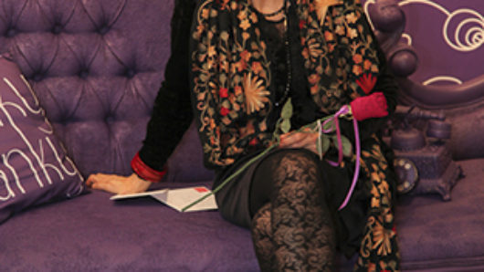 a photo of an older woman sitting on a purple couch