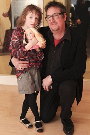 photograph of a father with his daughter, who is holding a doll in her hands