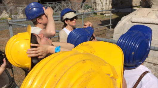 A photo of people visiting a construction site and wearing yellow and blue protective hats.