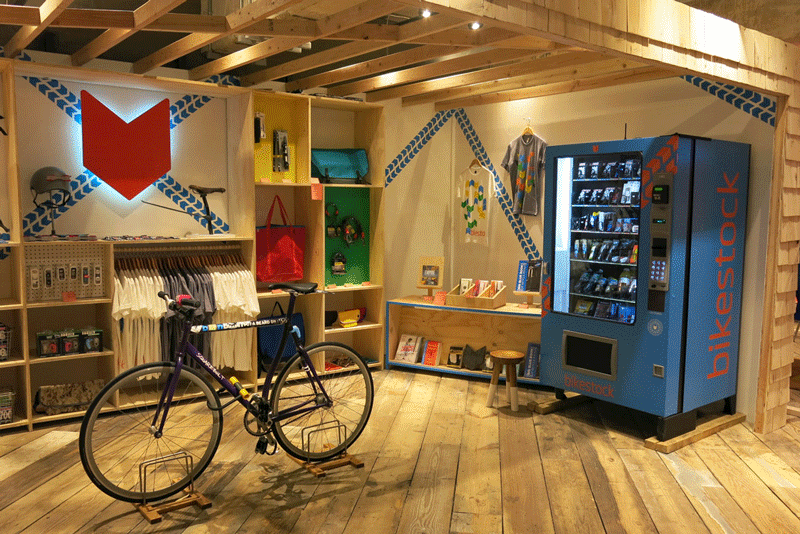 Interior of a shop with a bike, t-shirts for sale, a vending machine, etc.