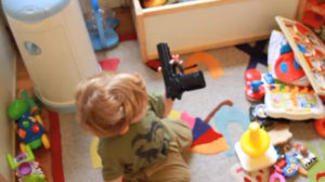 baby holding toy gun on a playroom