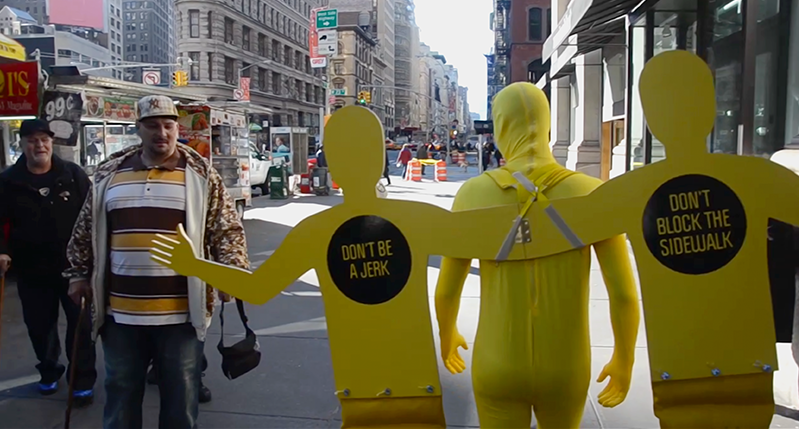 yellow men in costume on the right walking in street and two men on the left