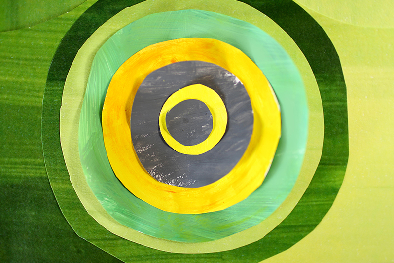 A set of, black, yellow, lime and green colored circles made from overlapping pieces of paper.