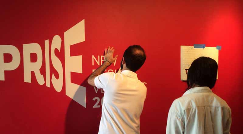 a man pressing vinyl letters on a red wall