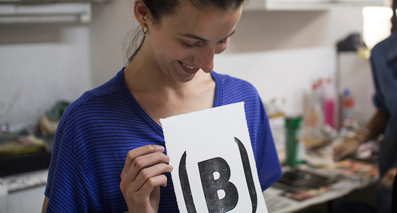 student holding a print with letter B