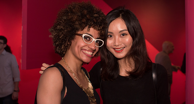 two women smiling in a red background