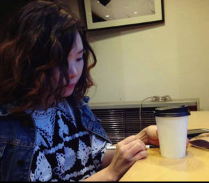 asian women writing on coffee cup