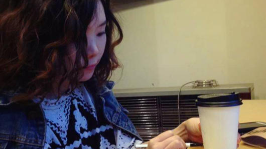 asian women writing on coffee cup