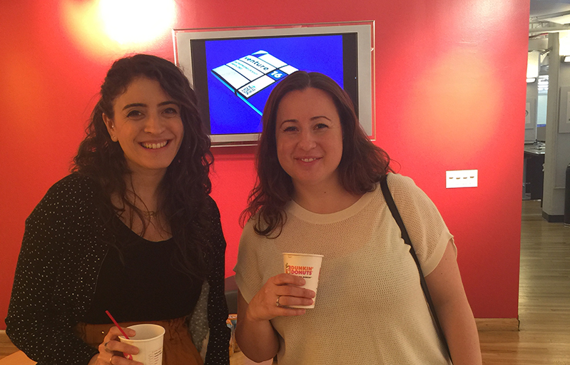 A photo of two smiling women holding some coffee cups.