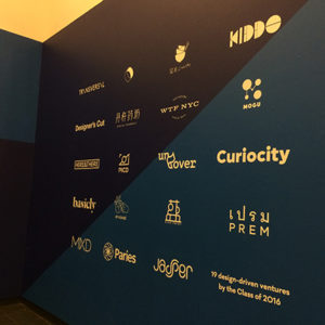 A logo poster colored in black, blue and yellow, that covers an exhibition wall.