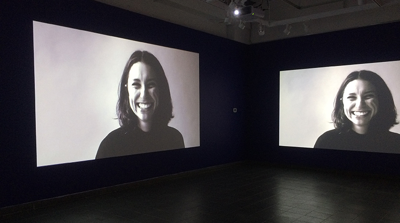 an image of a woman in black and white projected on two walls in a dark room