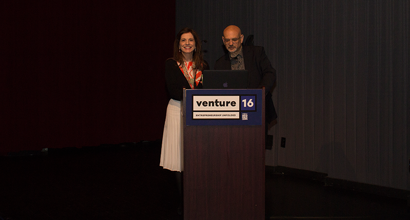 a man and a woman giving a speech on a stand in the venture 16 event