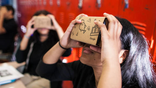 A group of students trying some cardboard 3D virtual reality glasses.