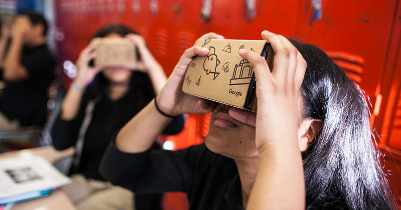 A group of students trying some cardboard 3D virtual reality glasses.