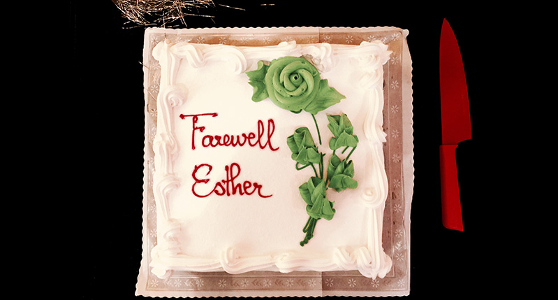 picture of a cake with a green rose on it and written in red is Farewell Esther and near the cake is a red knife