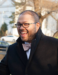 A photo of a man wearing glasses and a coat.