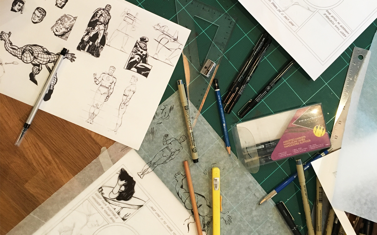 A photo of an artist work bench with pencils, rulers, paper and some cartoon sketches of heroes.