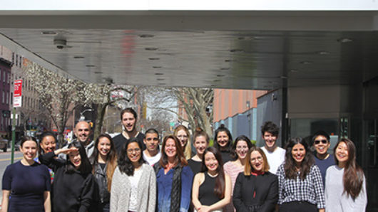group photo of students and alumni on the sidewalk