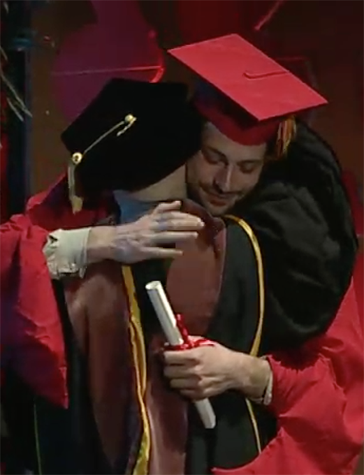 A photo of a grad student and a teacher hugging and congratulating each other.