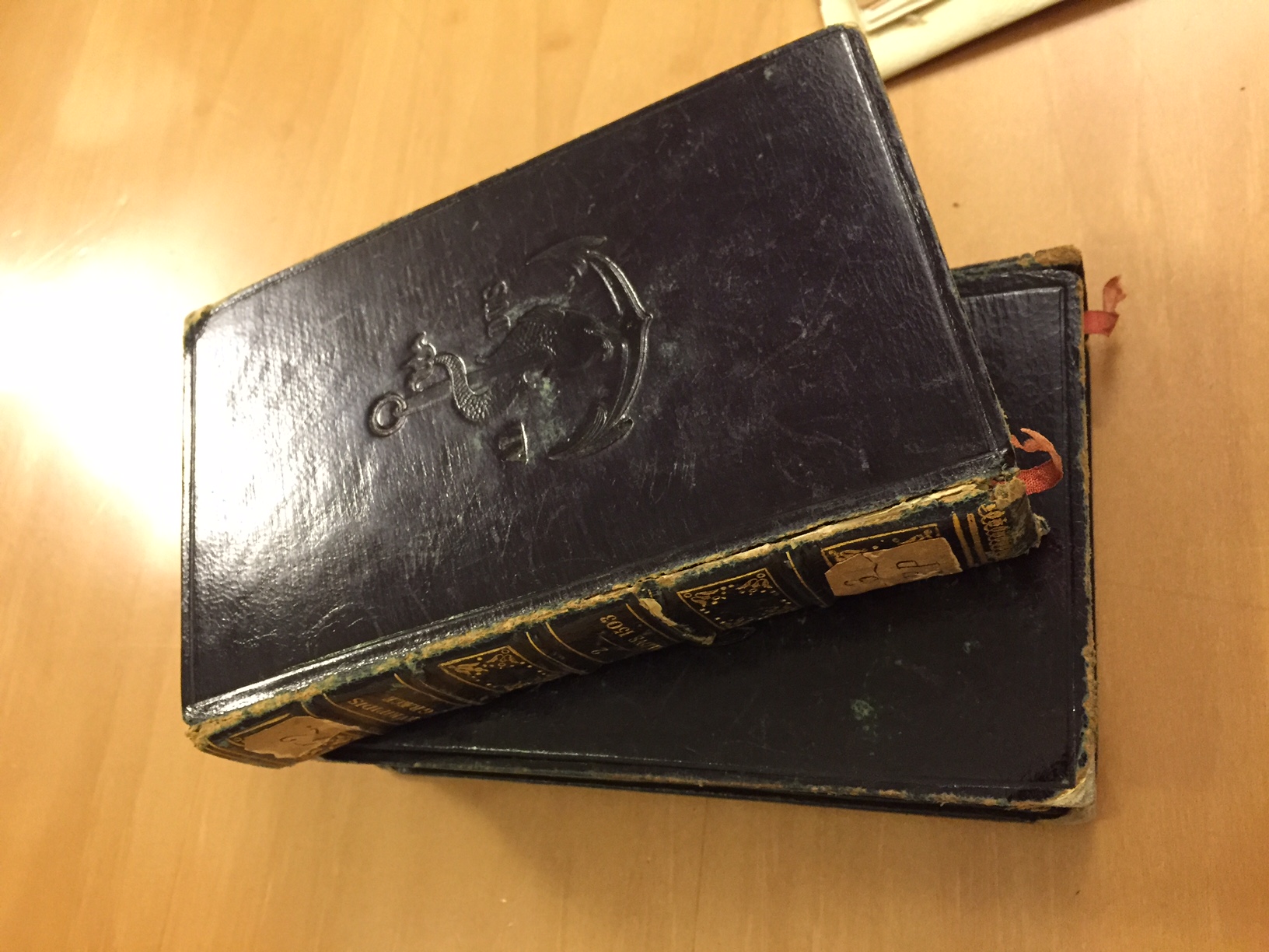 Old books with black cover and embossed seal on them.