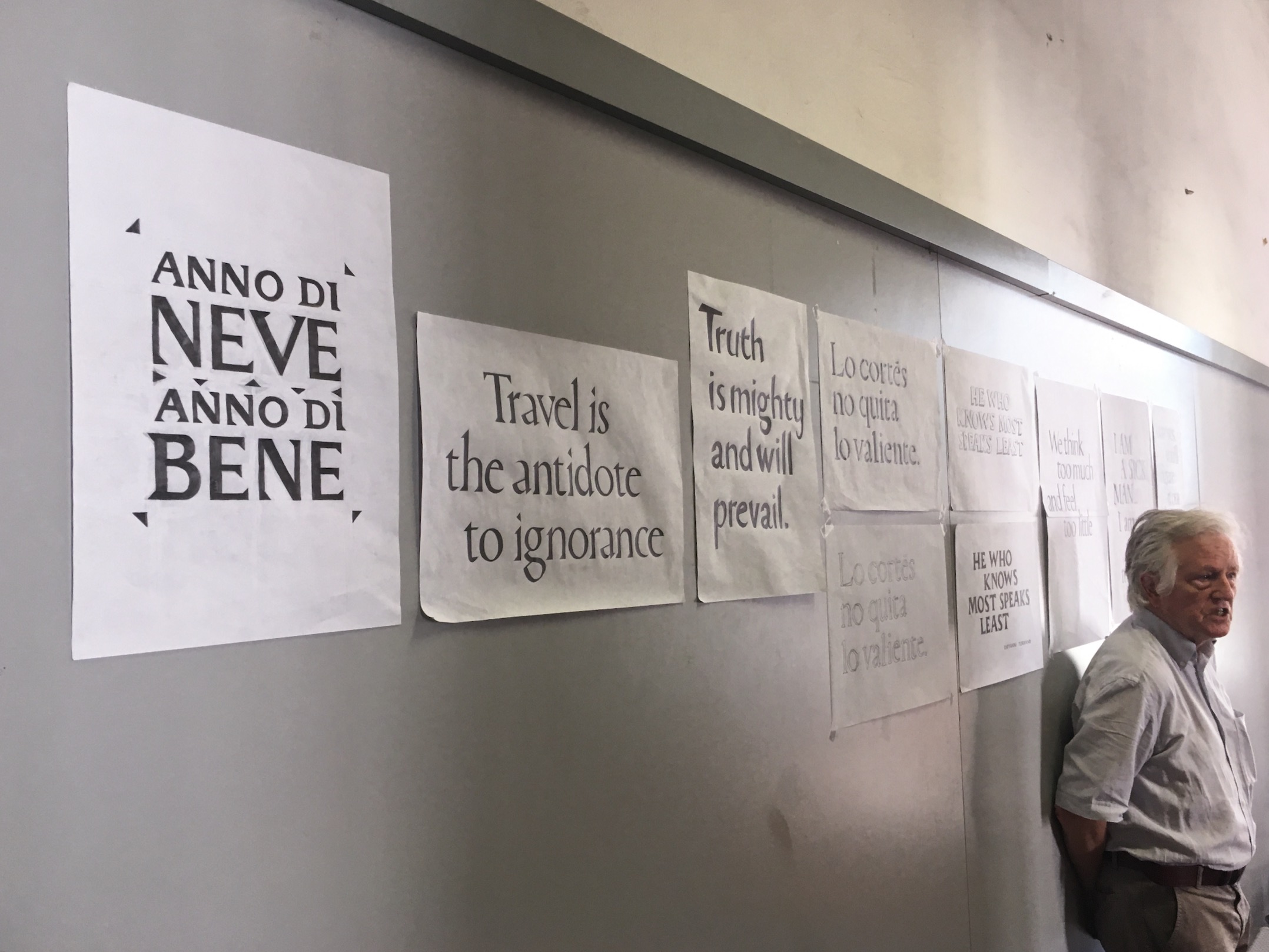 A wall with papers on it that contain different styles of writing and text.
