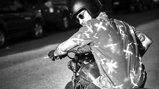 A black and white photo of a man riding a bike.