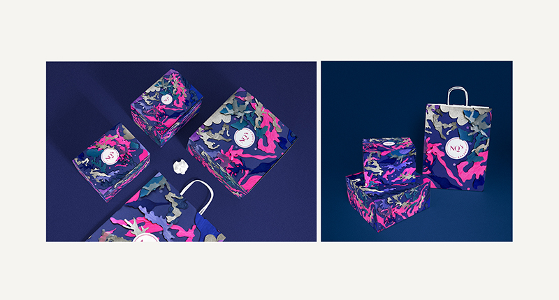 A photo of some bags colored with splashes of pink, blue, black and gray with a white circle and a logo on them.