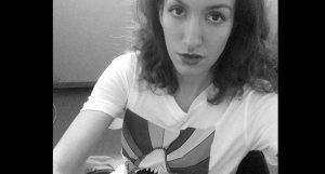 A black and white photo of a woman wearing a t-shirt with a drawing on it.