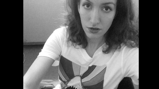 A black and white photo of a woman wearing a t-shirt with a drawing on it.