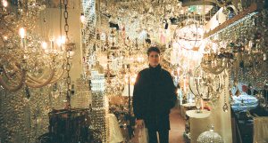 A photo of a man standing in a glass chandelier shop.