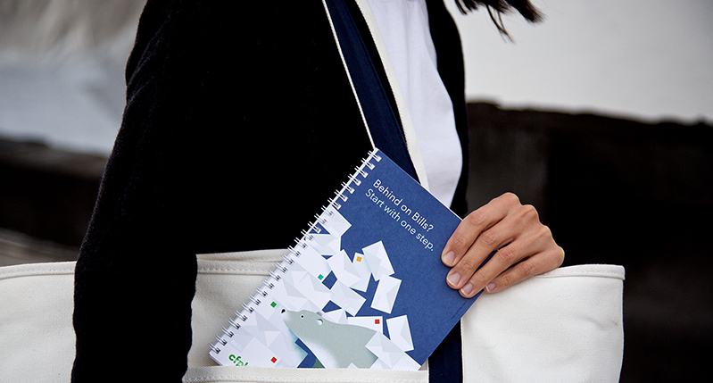 A photo of a woman holding a bag and a blue and white colored notebook.