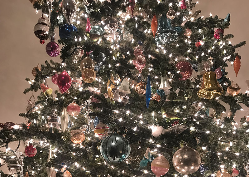 A photo of decorated Christmas tree with bright white lights and colorful  globes.