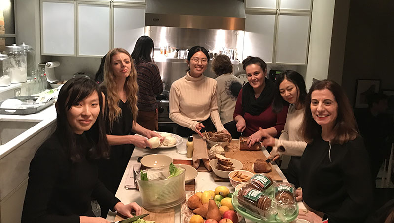 A photo of a group of people standing around a dinner table.