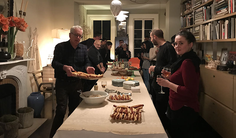 A photo of a group of people standing around a dinner table.