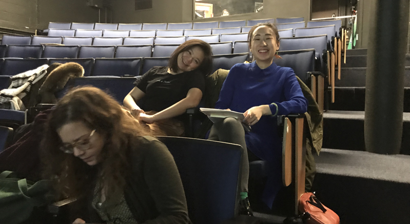 A photo of a group of people sitting in a theater room.