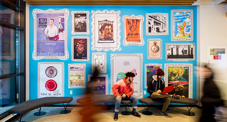 A photo showing people siting or walking by a blue wall filled with posters with old photo frames.