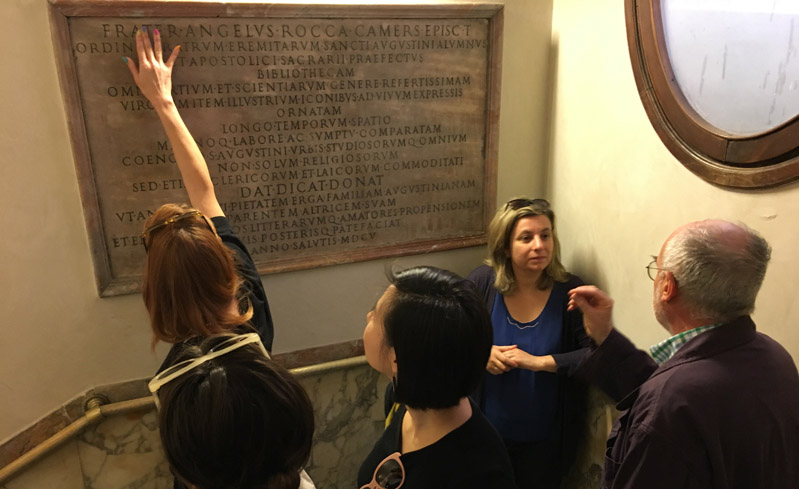 A photo of some students checking an engraved plaque on the wall.