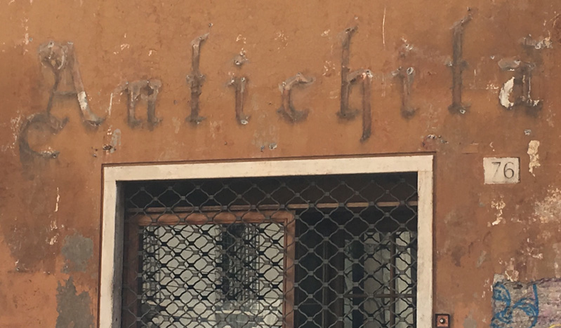 A photo of an old shop closed by a fence and some text over the door.