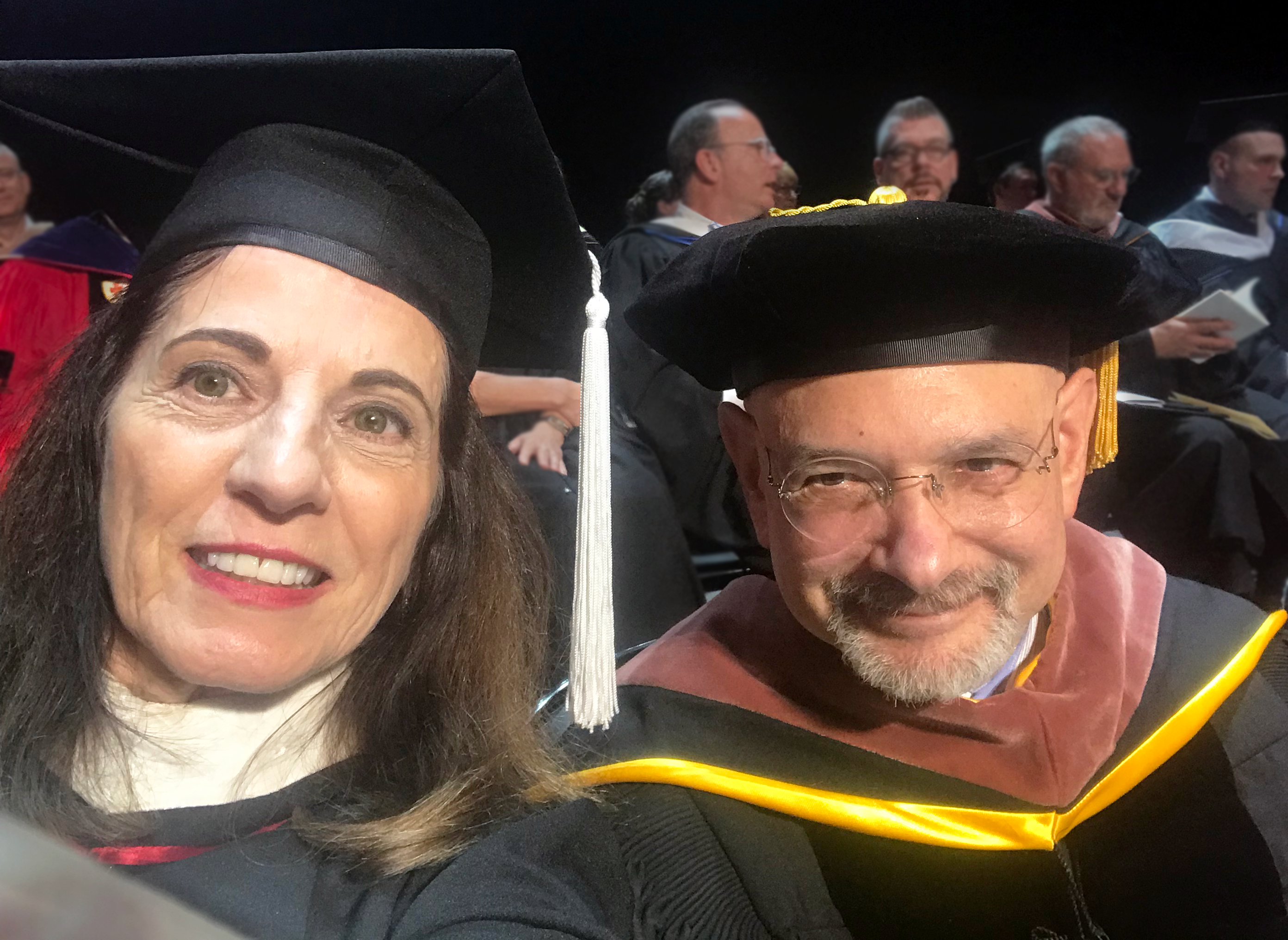A photo of two teachers wearing academic robes and hats for the graduation ceremony.