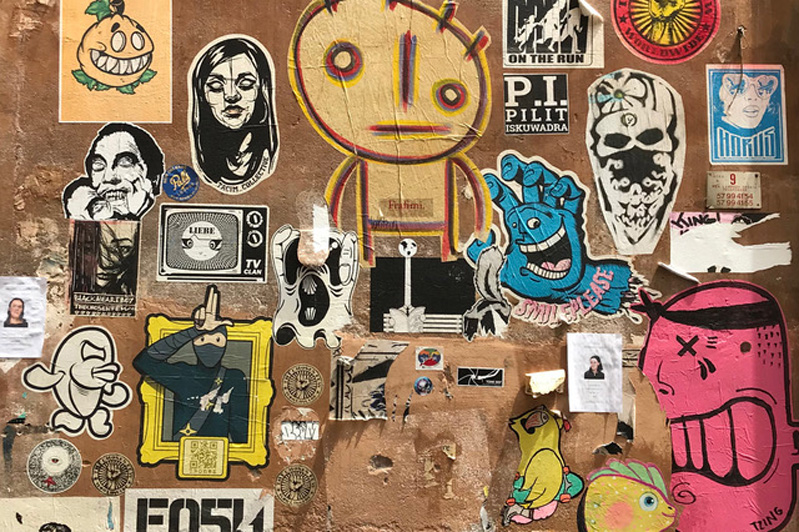 A photo of a wall filled with colorful stickers depicting people or animals.