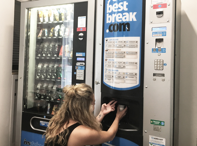 A photo of a woman at a beverage wending machine.