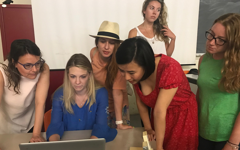 A group of people sitting around a laptop and looking at something.