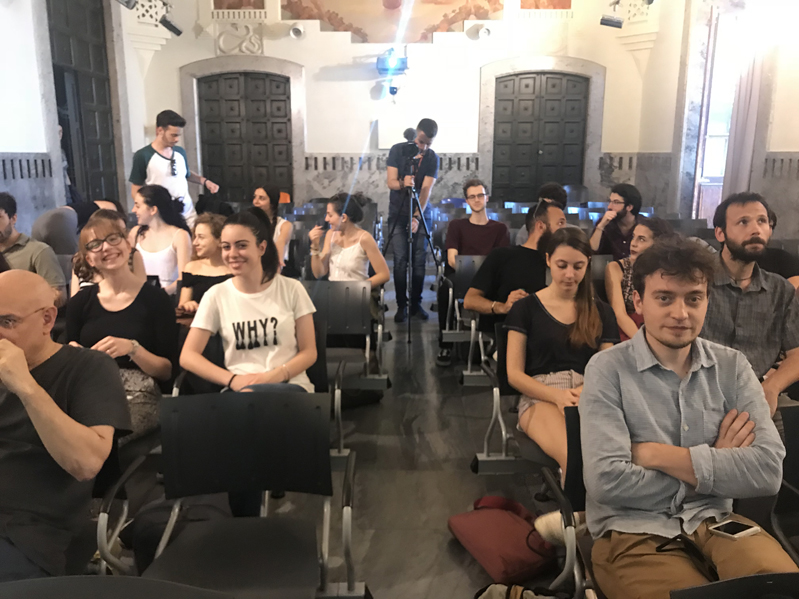 A photo of a group of people sitting on chairs in a room and waiting to listen a lecture.