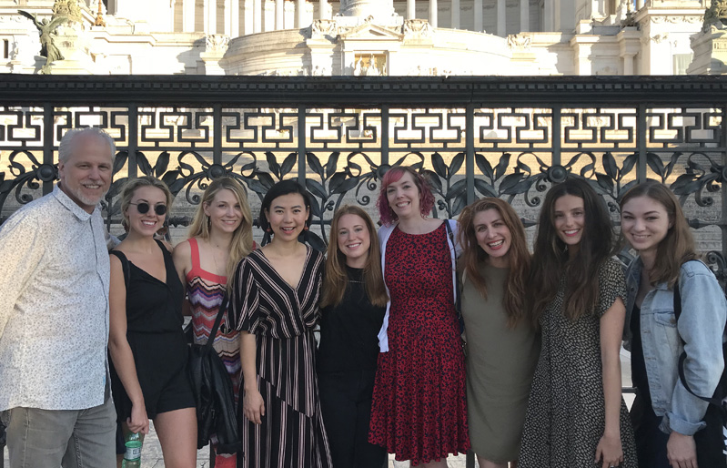 A photo of a group of people standing in front of some ancient building.