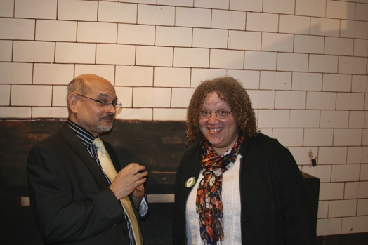 Photograph of a man and a woman in front of a white wall.