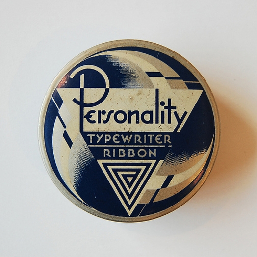 A button with a black and white triangle shape and a text that says: Personality Typewriter Ribbon.