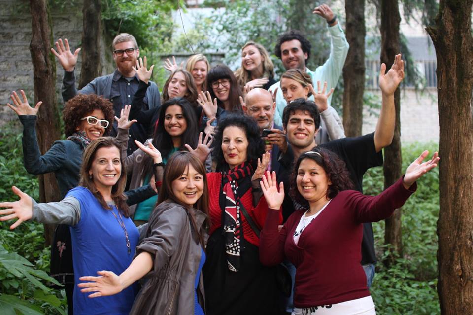 A photo of a group of people standing in a green park among some trees.