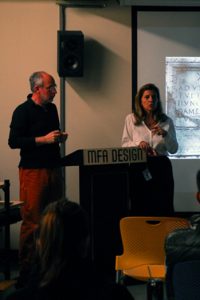 A man and a woman giving a MFA Design lecture while behind them is a screen projection.
